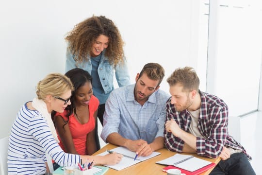 Five people reviewing notes at table