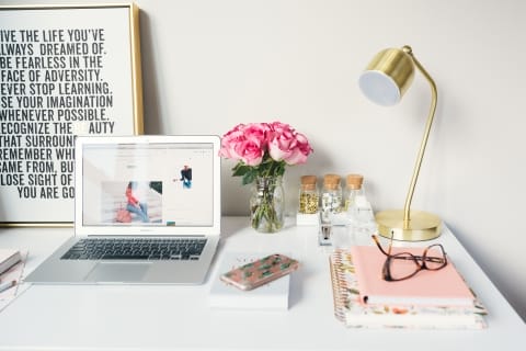 Desk with laptop, flowers, notebooks and lamp