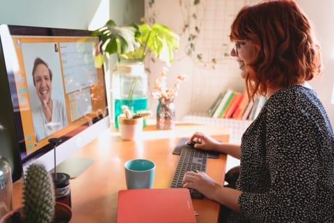 Woman smiling at an image of a coworker on her computer screen