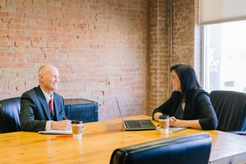 Colleagues sit and talk at conference table