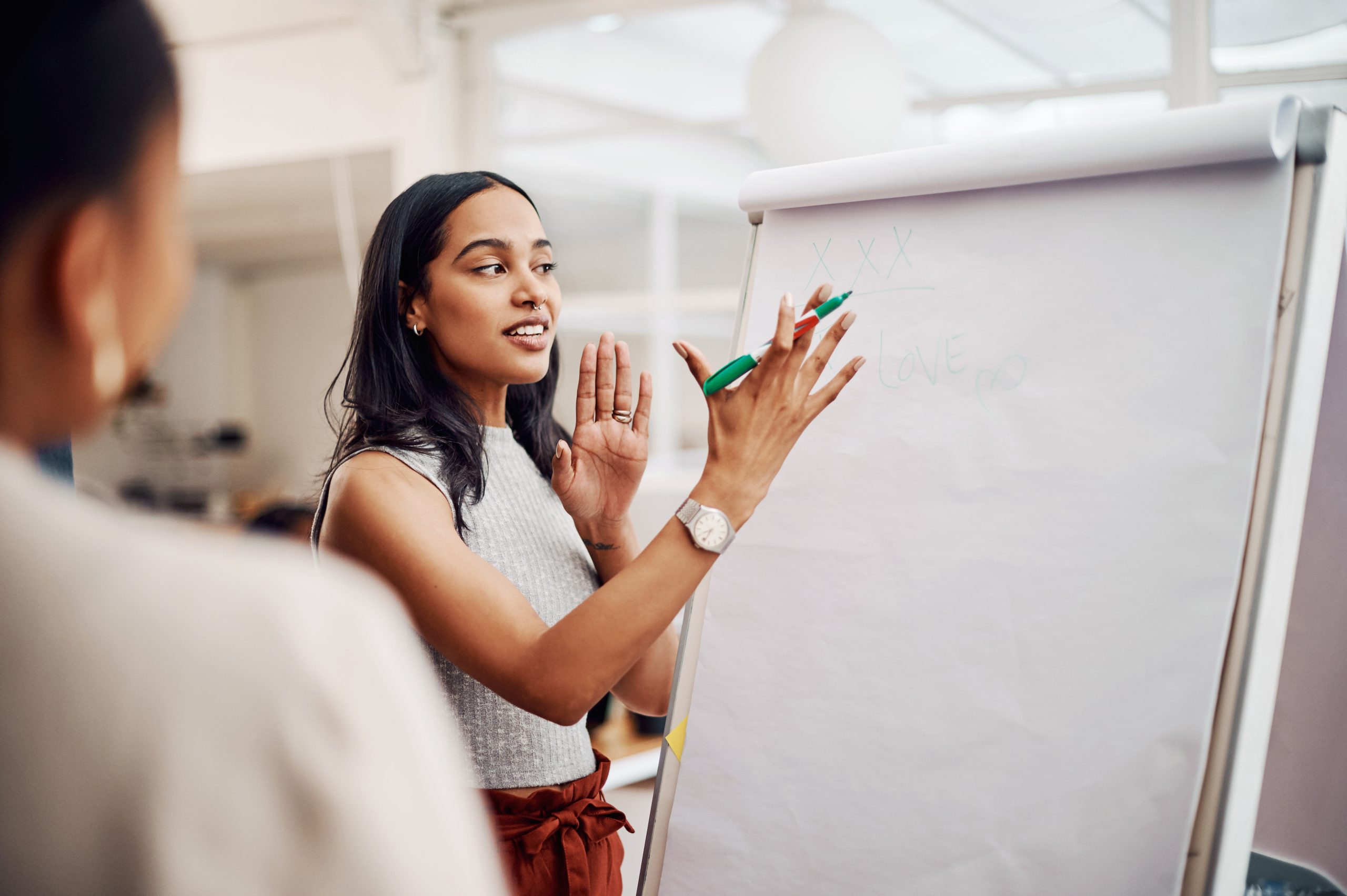 Woman, mentor and whiteboard in office for training, teaching and learning for skill or career development. People, employee and coach or leader at workshop with internship program and motivation.