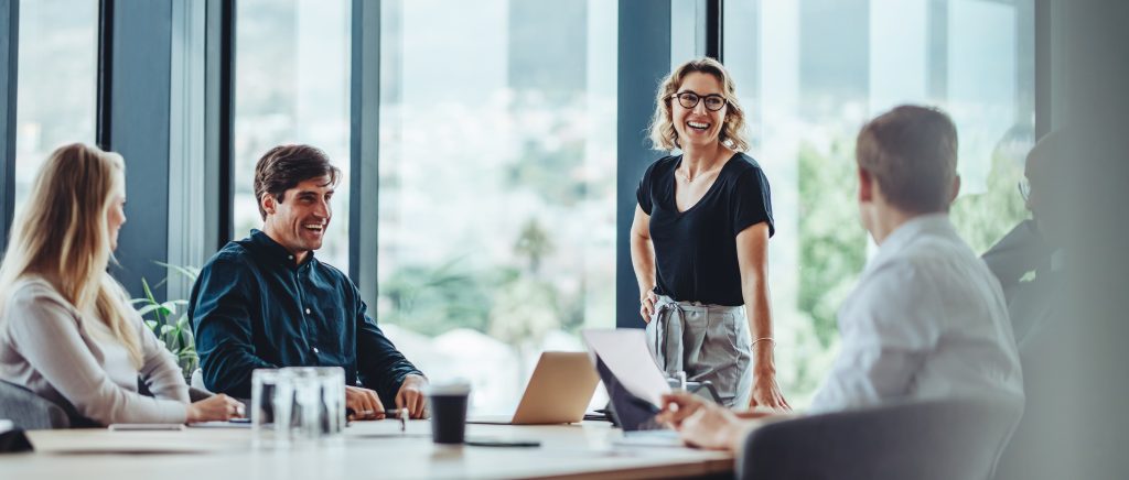 Group of colleagues engaging in a discussion during a business meeting in a conference room. Happy business people, men and women, collaborating and working towards their shared goals.